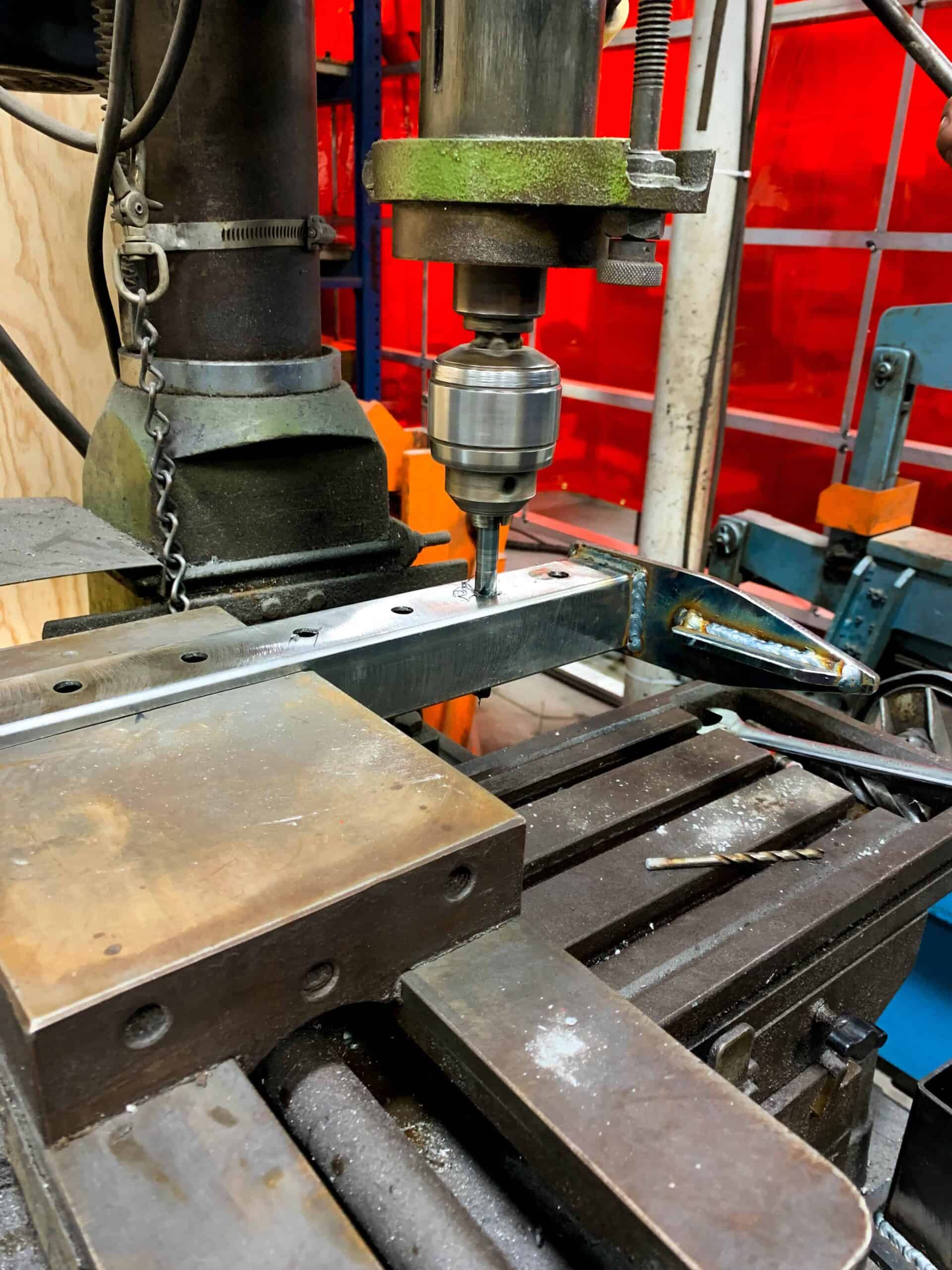 a drill pressing down on metal to carve a hole